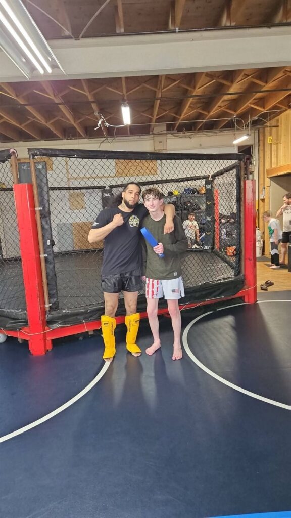 Coach Jarred McQuitter congratulating a student on a belt promotion