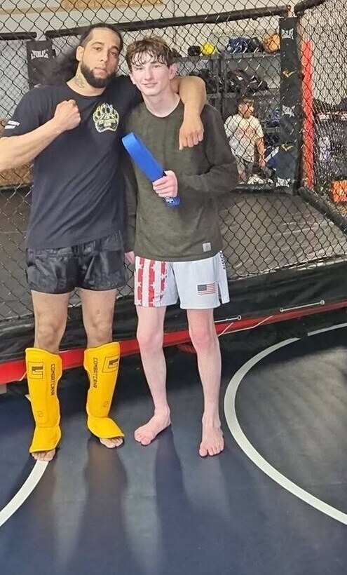 Coach Jarred McQuitter congratulating a student on a belt promotion